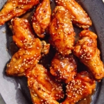 Air fryer chicken wings on a platter with beer next to it.