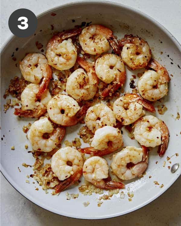 Shrimp being cooked in a skillet for shrimp scampi.