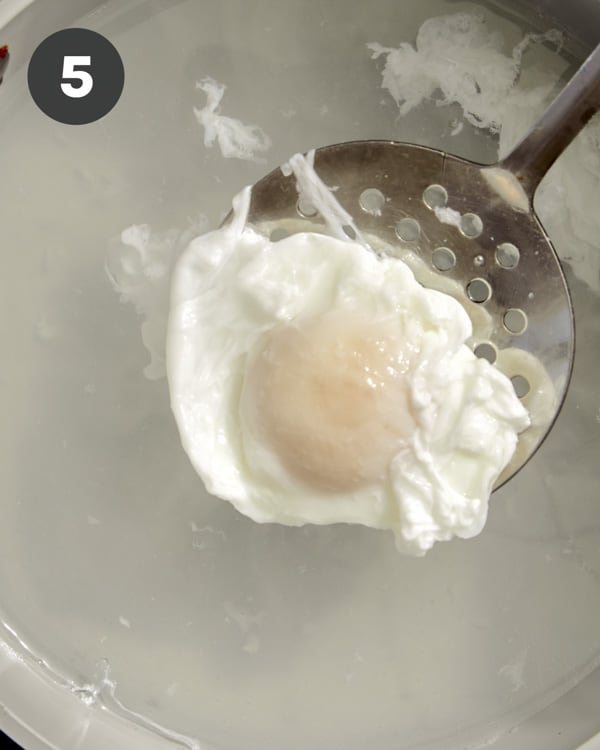 Using a slotted spoon to take out a poached egg. 