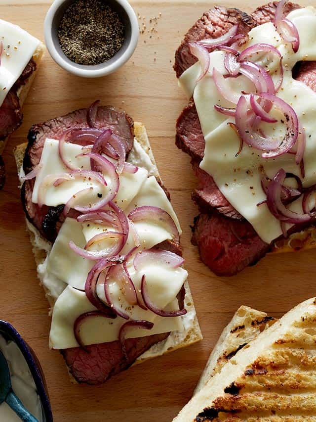tri tip over bread and cheese on a cutting board