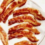 Bacon draining on a backing sheet with paper towels.