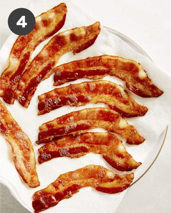 Bacon draining on a backing sheet with paper towels.