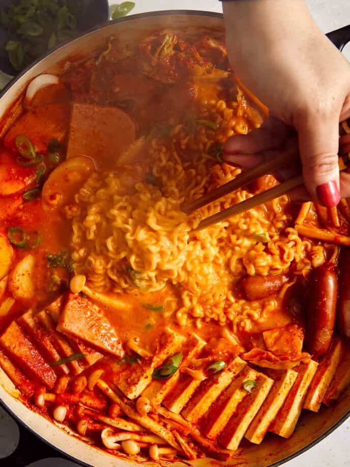 Budae Jjigae being mixed together with chopsticks. 