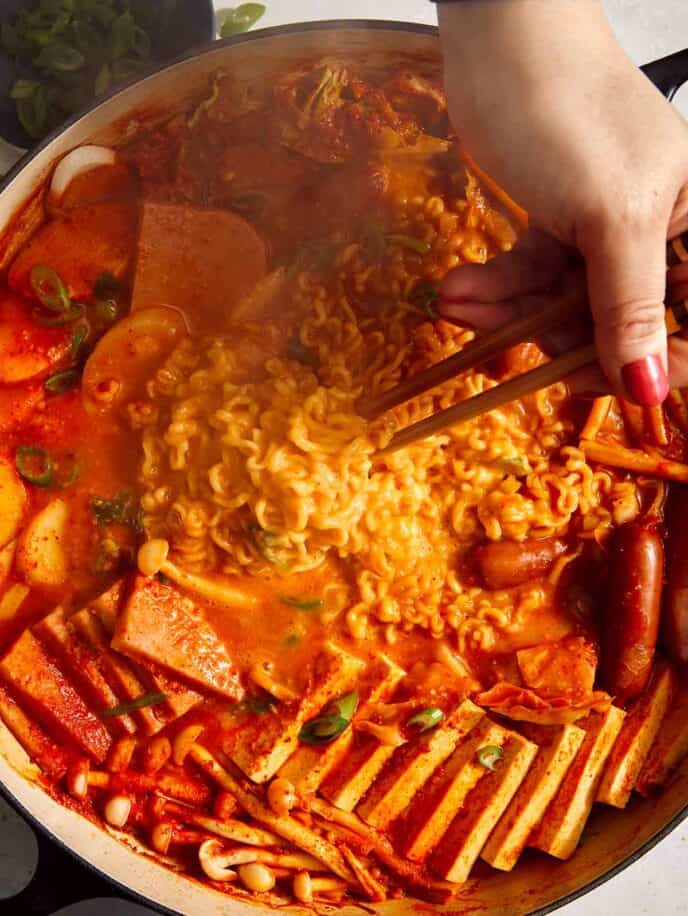 Budae Jjigae being mixed together with chopsticks.
