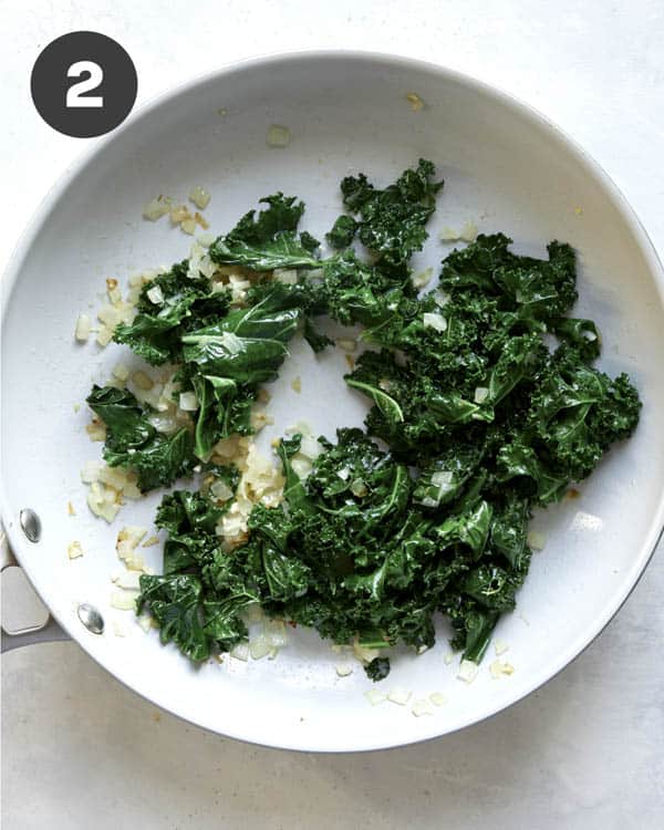 Kale with onions and garlic cooking in a skillet.