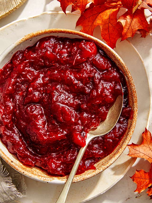 cranberry sauce in a bowl with a spoon and maple leaves