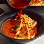 Korean army stew or Budae Jjigae being ladled into a bowl.