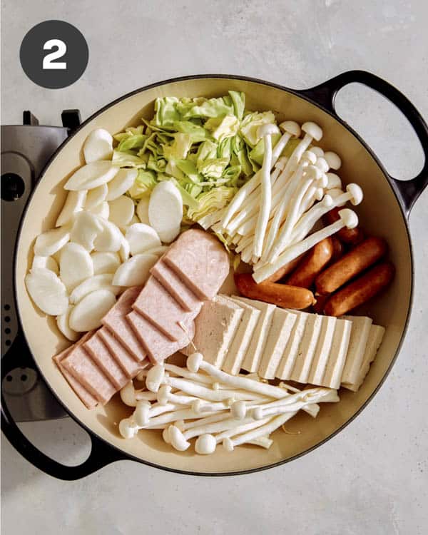 Korean army stew with ingredients in a skillet. 