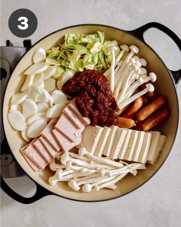 Korean army stew in a skillet with paste over it. 