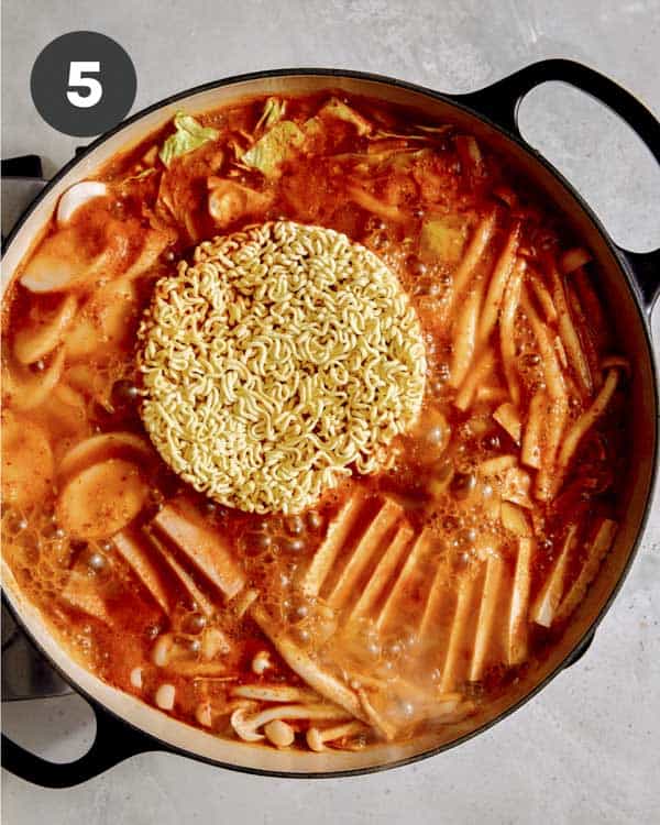Budae Jjigae with noodles cooking in a skillet.