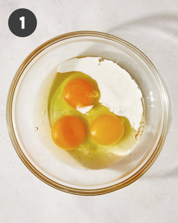 Eggs cracked into a bowl with cream.