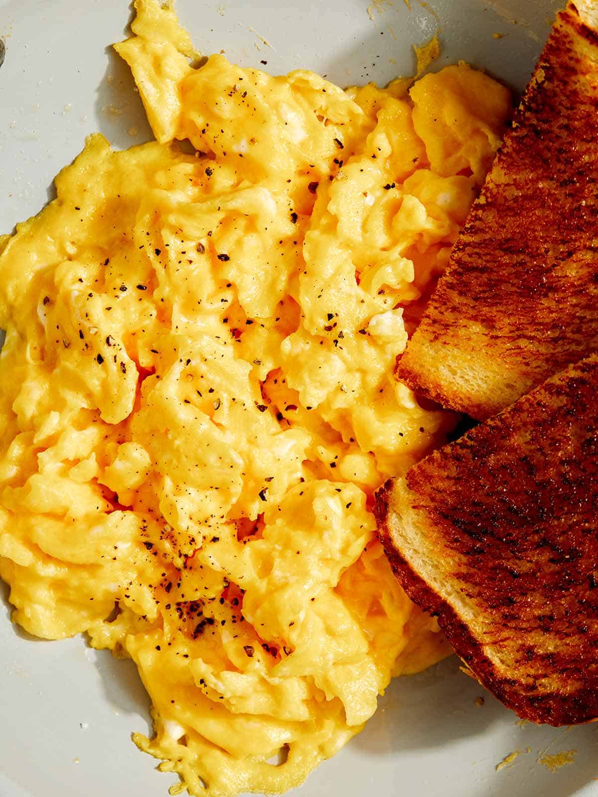 Scrambled eggs in a skillet with toast. 