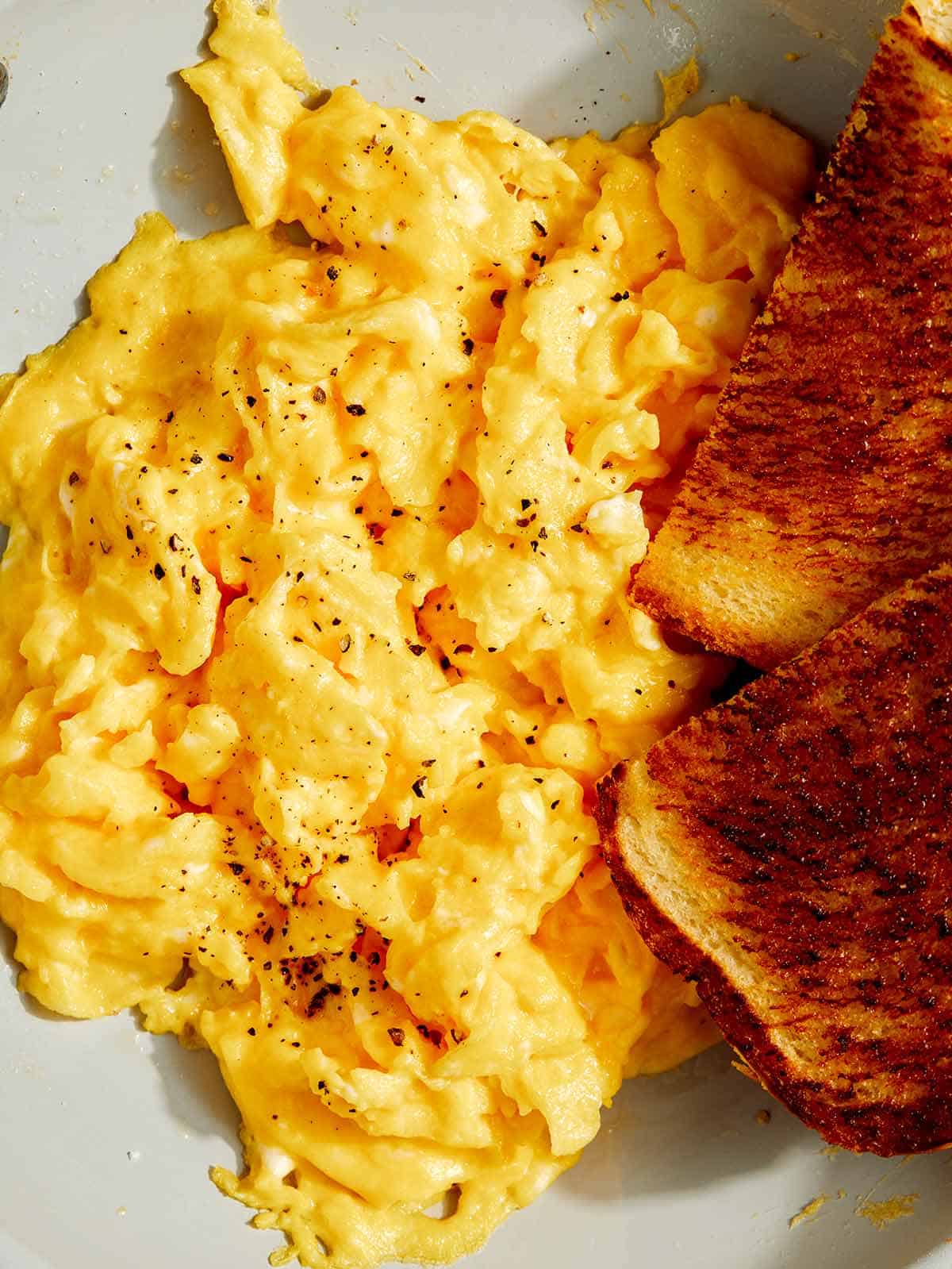Scrambled eggs in a skillet with toast.