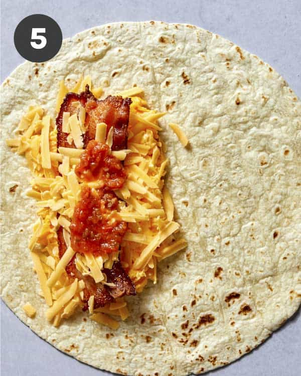 Salsa spread on the filling of a breakfast burrito.