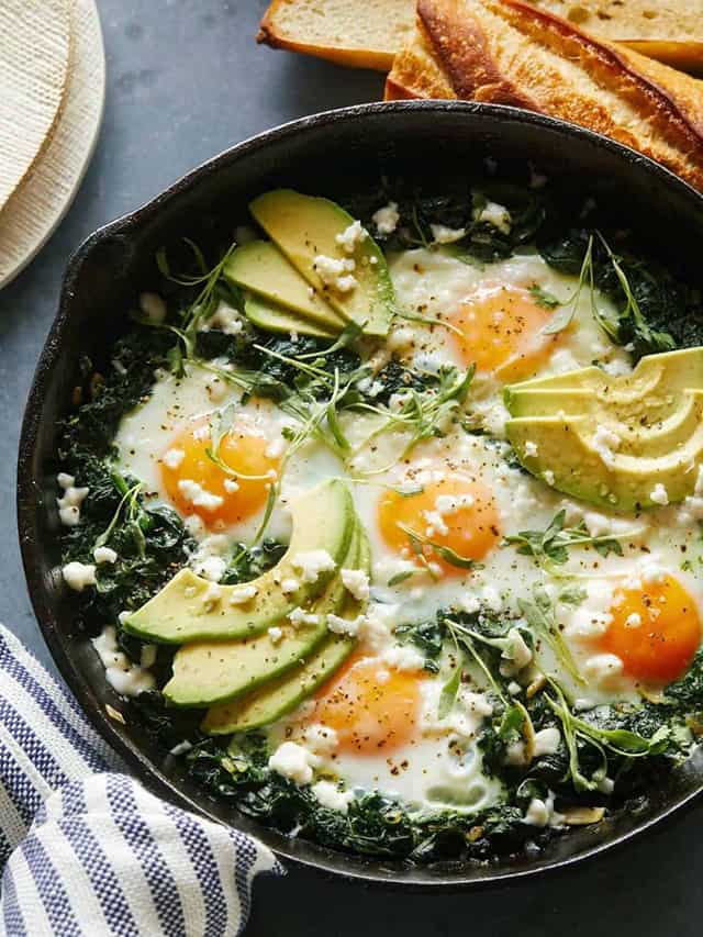 eggs and avocados on a skillet with plates and napkins