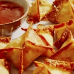 Air fryer crab rangoons with a dipping sauce on the side.