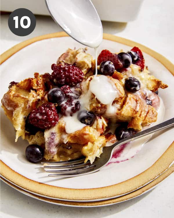 Bread pudding on a plate with glaze being spooned on. 