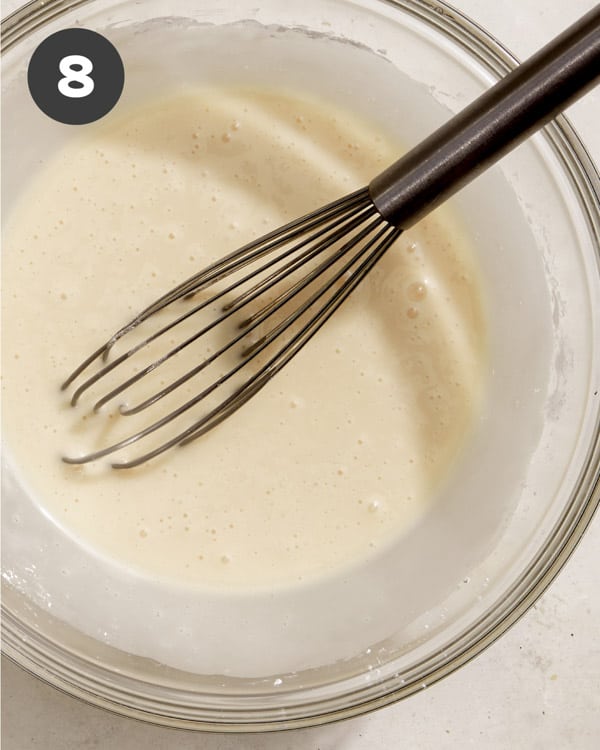 Bread pudding glaze in a bowl with a whisk.