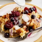 Bread pudding on a plate with glaze being spooned on.