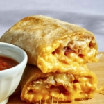 A breakfast burrito cut in half with cheese oozing out.