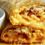 A breakfast burrito cut in half with cheese oozing out.