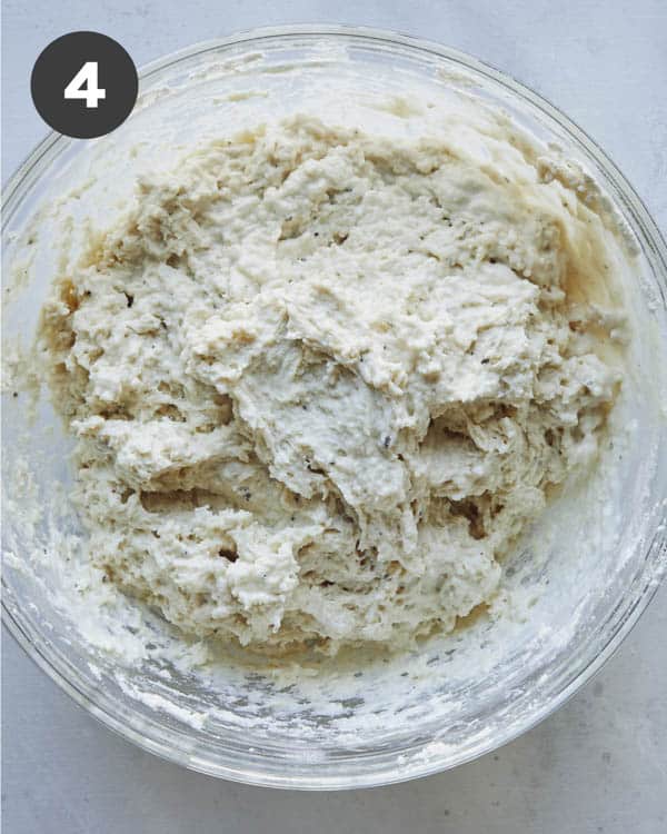 Drop biscuit dough combined in a glass bowl looking sticky.