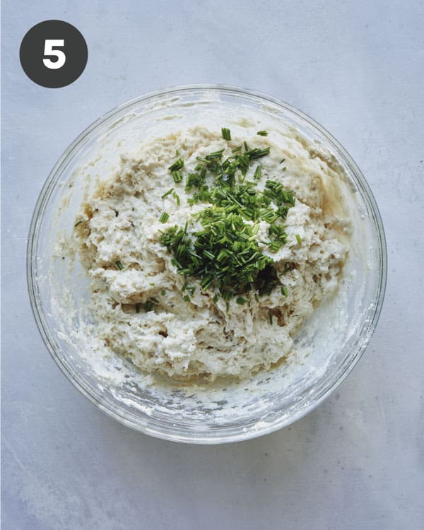 Drop biscuit dough in a bowl adding chives.