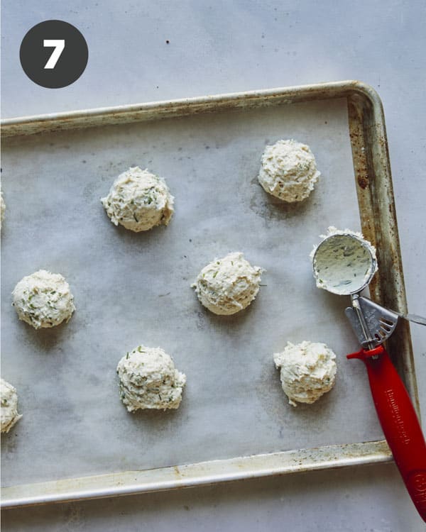 Drop biscuit dough scooped onto a parchment lined baking sheet.