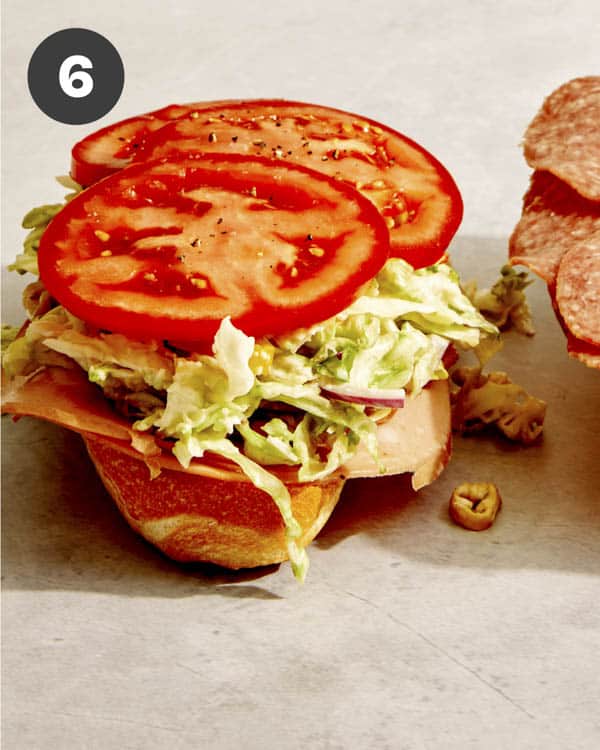 Tomato and slaw on top of a sandwich to make a Grinder.