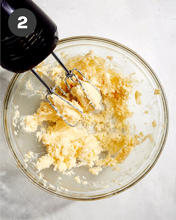 Honey butter in a glass bowl being beaten with a hand mixer.