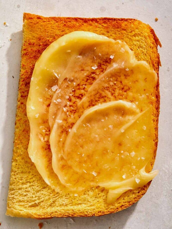 Honey butter on top of a half slice of toast.