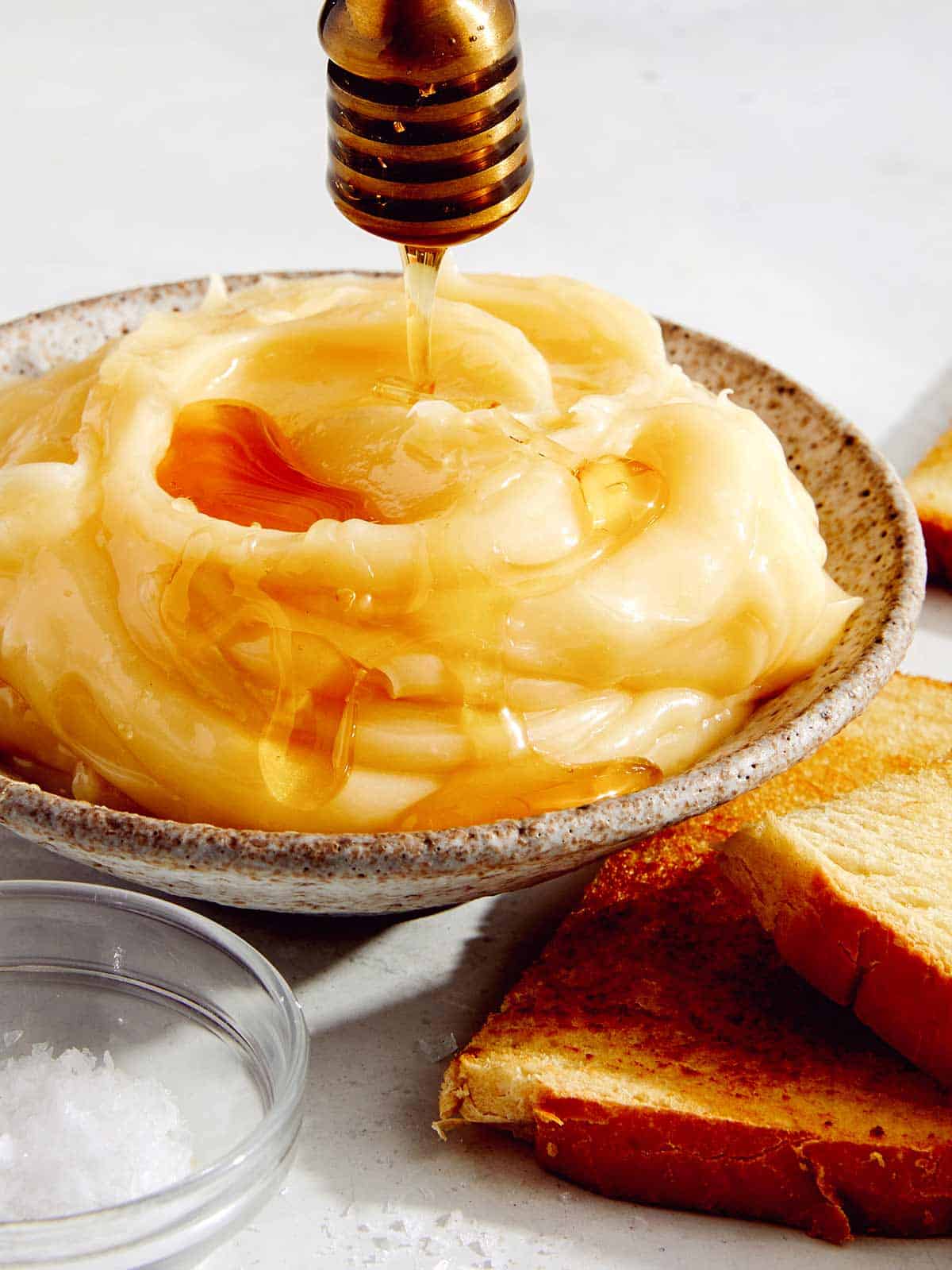 Honey butter in a bowl with honey and salt on top. 