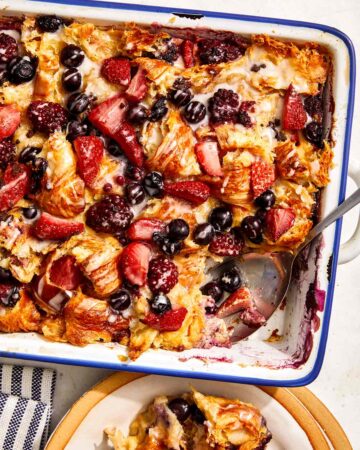 Triple berry bread pudding in a baking dish with a scoop out.