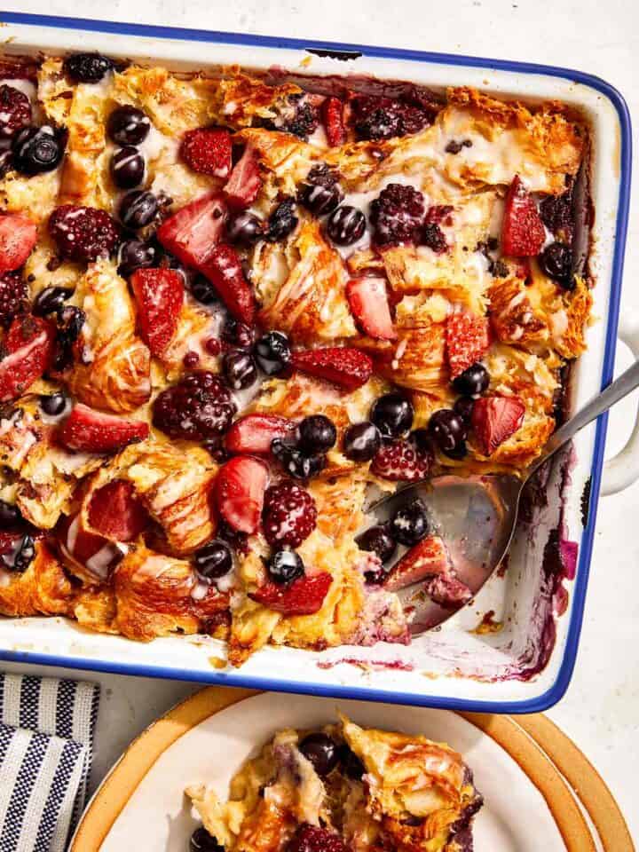 Triple berry bread pudding in a baking dish with a scoop out.