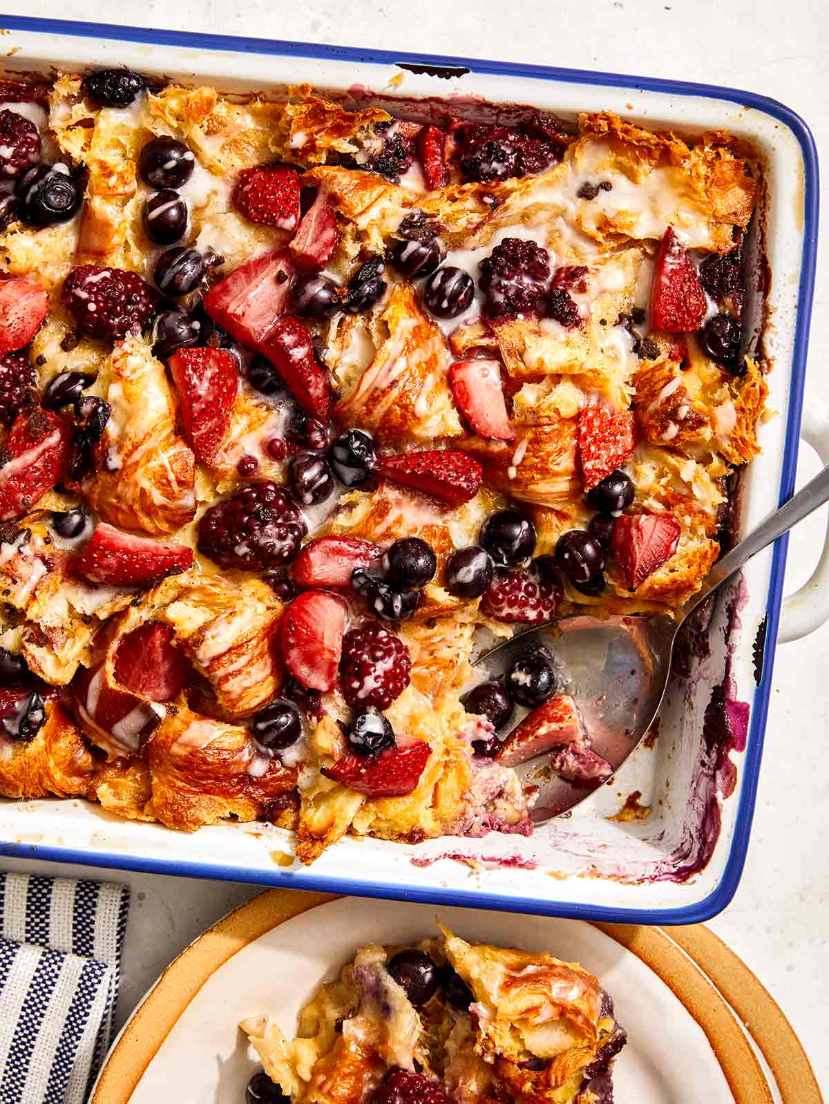 Triple berry bread pudding in a baking dish with a scoop out. 