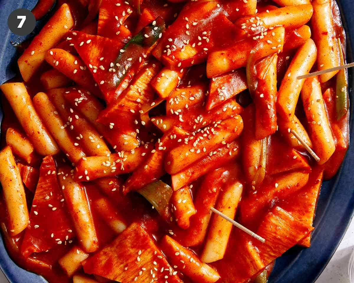 Tteokbokki served on a platter with sesame seeds on top.