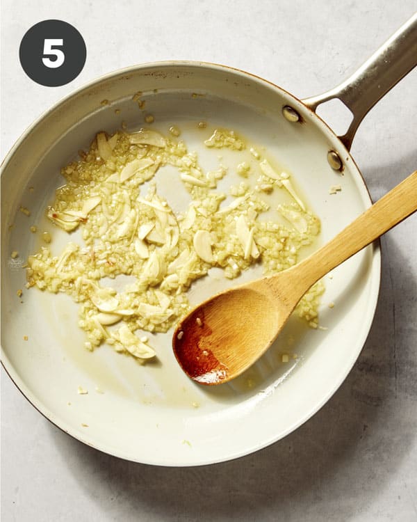 Garlic and shallots cooking in a skillet with butter and oil.