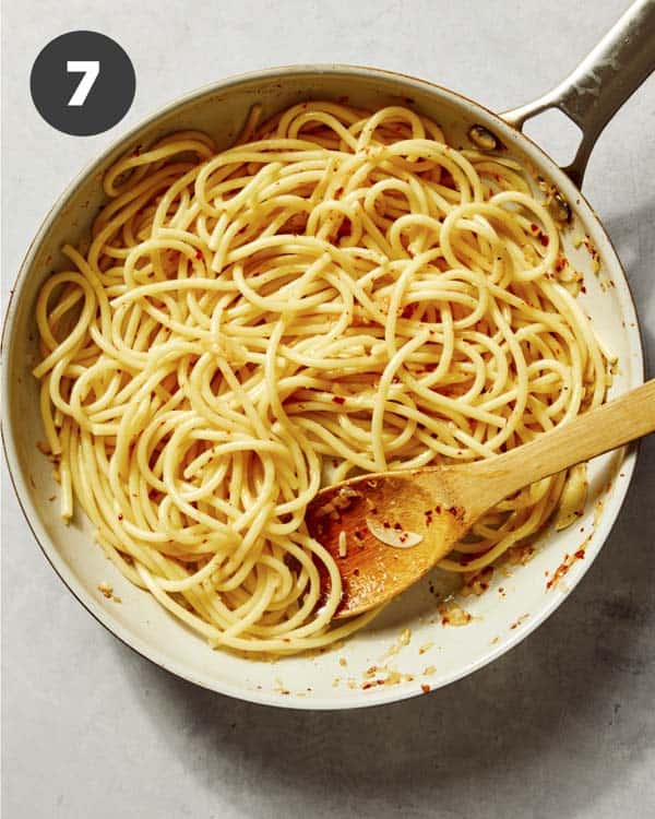 Garlic and lemon pasta being tossed together in a skillet. 