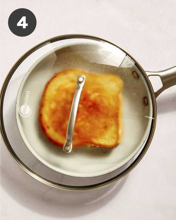 Grilled cheese in a pan with a top on to melt the cheese. 