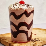 Chocolate milkshake in a glass with chocolate syrup.