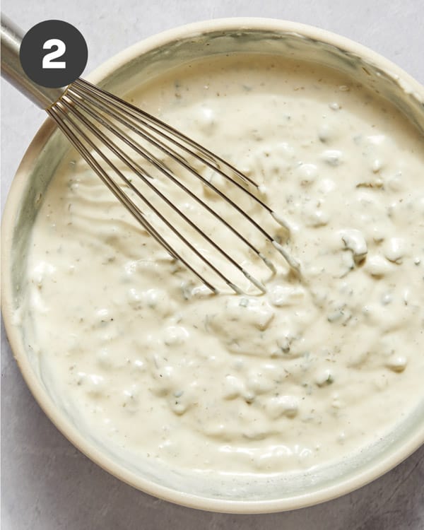 Freshly made tartar sauce in a bowl with a whisk.