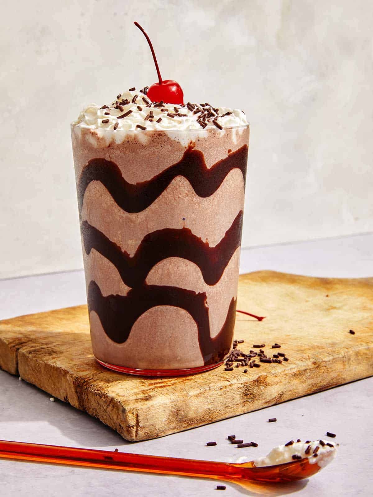 Chocolate milkshake in a glass with chocolate syrup.