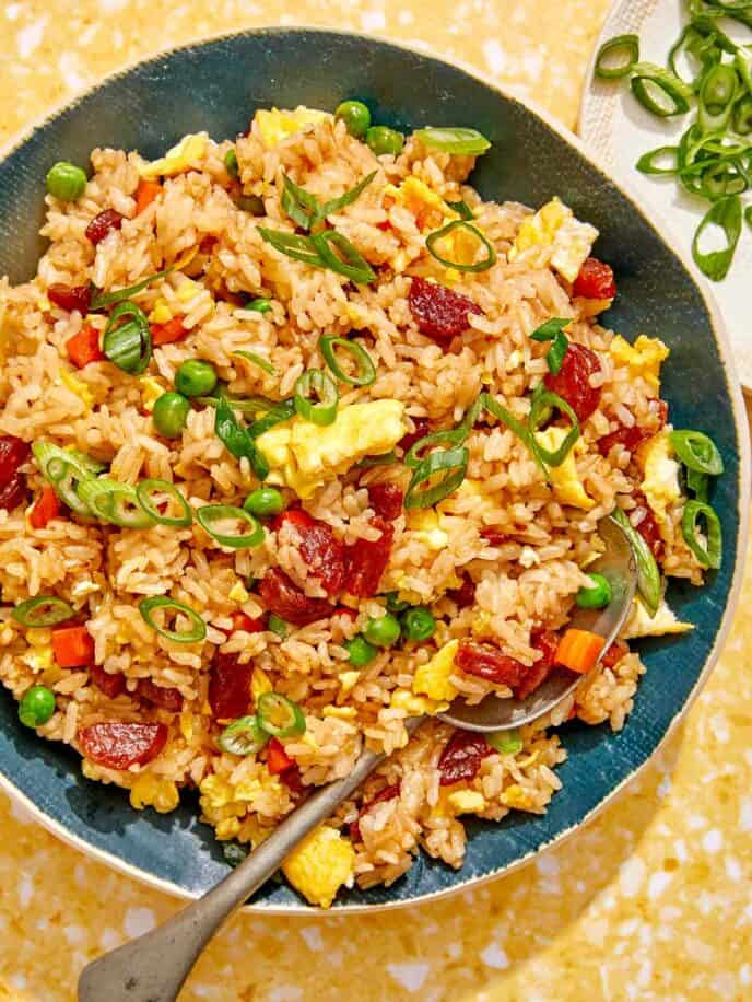 Fried rice in a bowl with green onions on the side.