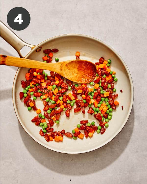 Sausage and veggies cooking in a skillet to make a fried rice recipe. 