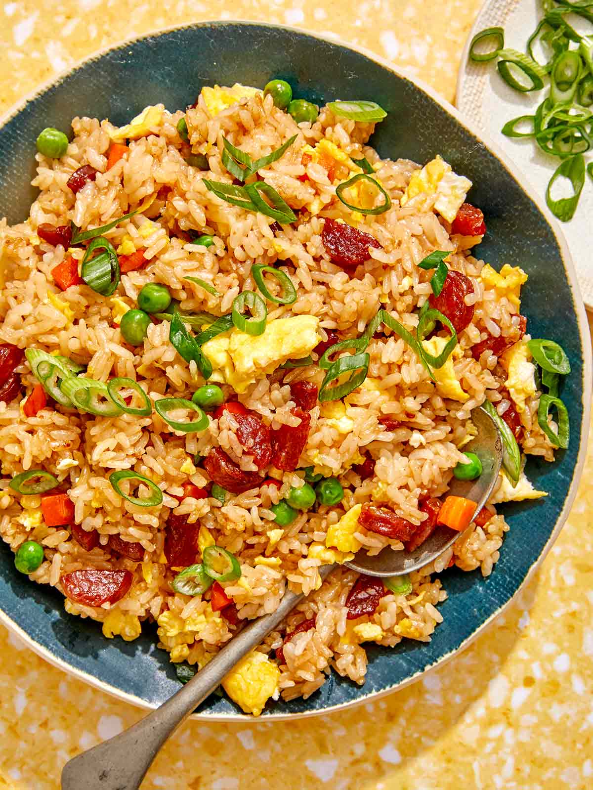 Fried rice in a bowl with green onions on the side. 