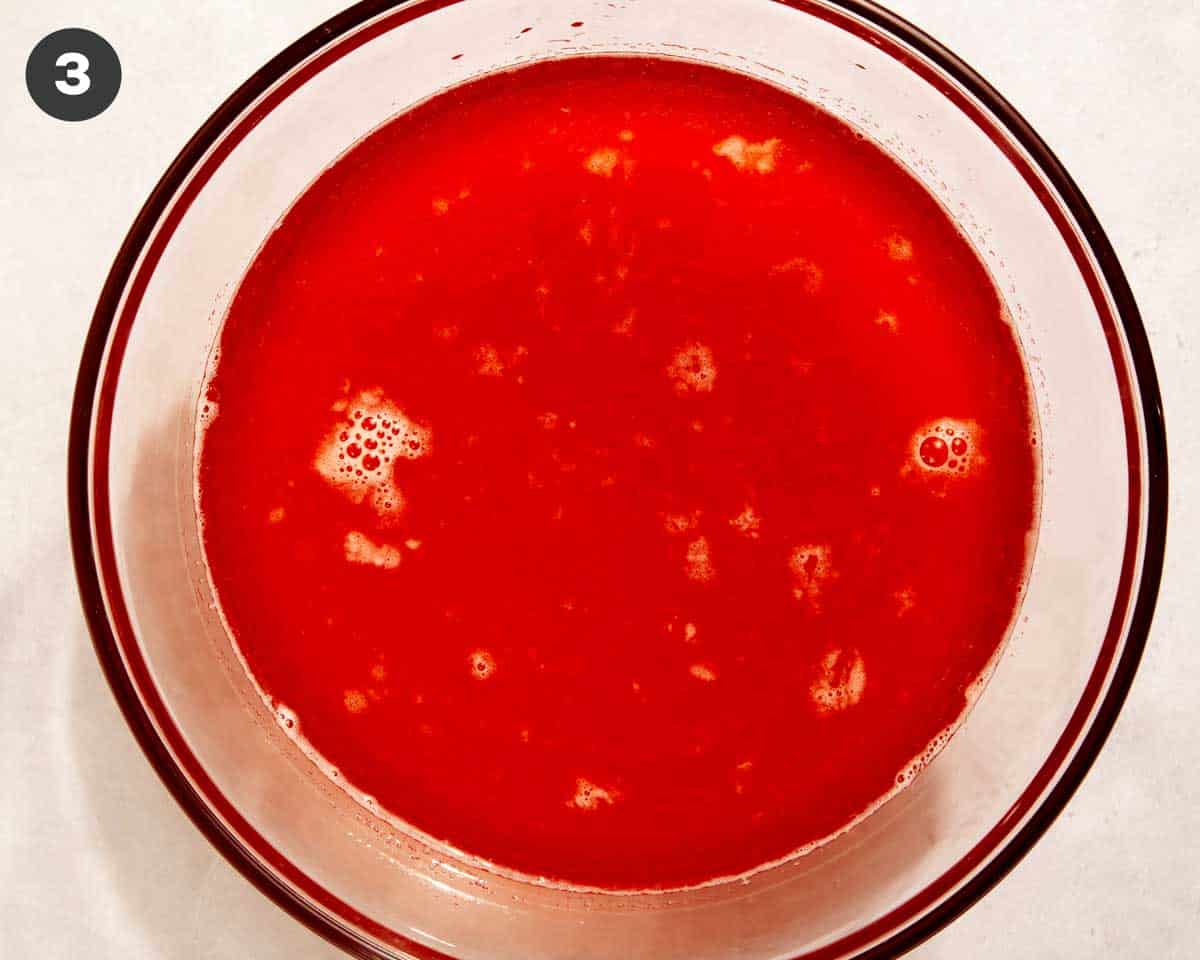 Strawberries strained into a bowl to make strawberry lemonade.