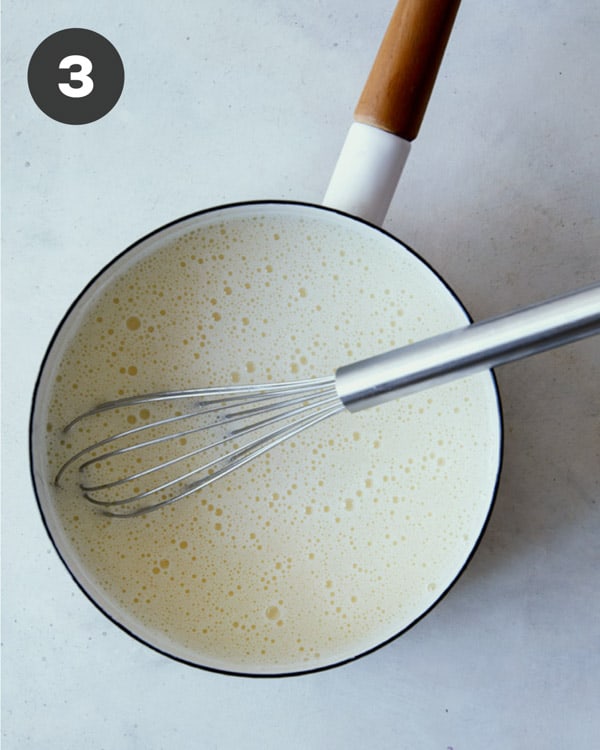 A pot shot overheat with a whisk in it showing how you add ingredients for banana pudding back into the pot.