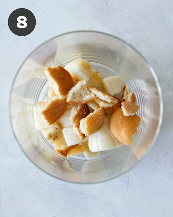 Adding crushed nilla wafers to a cup to make homemade banana pudding.