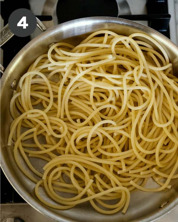 Bucatini noodles in a skillet. 