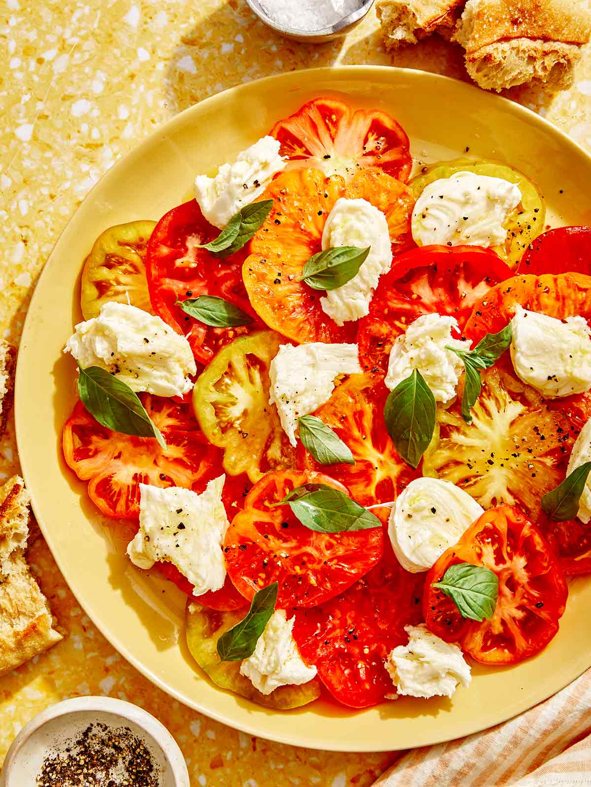 Caprese salad recipe on a platter with bread on the side. 